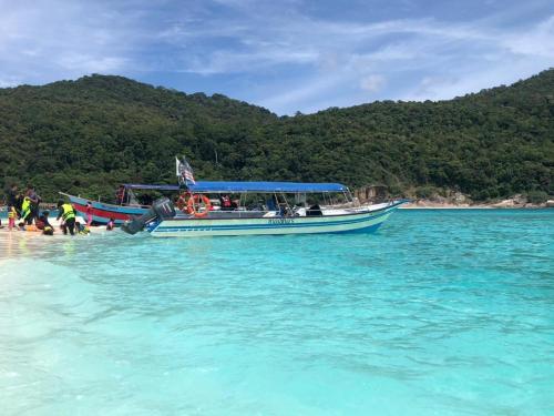 a boat in the water next to a beach at Marina's Redang Boat in Redang Island