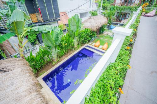 an outdoor swimming pool in a garden with plants at Shortcut Breeze Guest House in Canggu