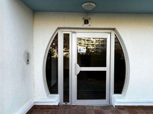 un accès à un bâtiment avec une porte en verre dans l'établissement Studio Cabine avec Terrasse et Piscine à 100m de la Plage à La Grande Motte - FR-1-716-56, à La Grande Motte