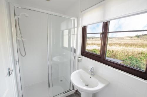 a white bathroom with a shower and a sink at Rockpool - Attractive and spacious retreat near Croyde beach - Sleeps 8 in Croyde
