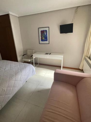 una camera con letto, scrivania e TV di Hostal Ochoa a San Adrián