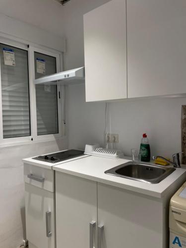 eine weiße Küche mit einer Spüle und einem Herd in der Unterkunft Apartamentos Cuna 21 in Sevilla