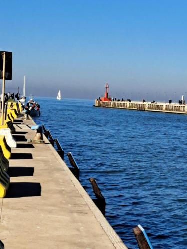 a pier with a boat in the water and a lighthouse at Holidays at the Dock - Fiumicino Airport in Fiumicino