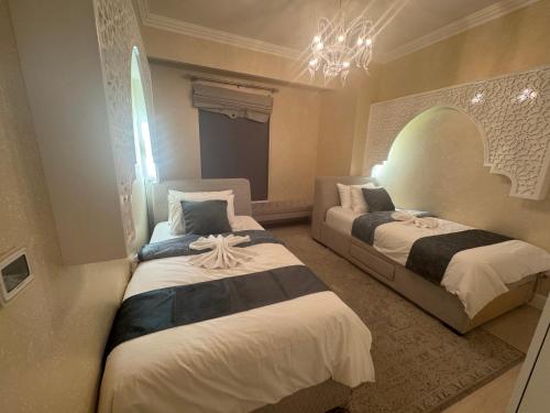 a bedroom with two beds and a chandelier at ROYAL BEACH RESIDENCES 2 in Dubai