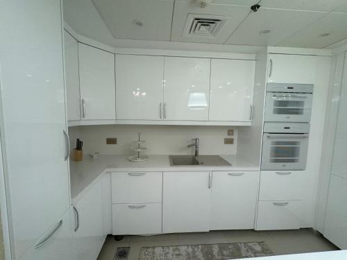 a white kitchen with white cabinets and a sink at ROYAL BEACH RESIDENCES 2 in Dubai