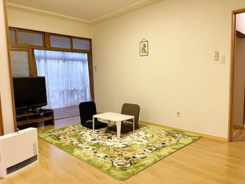 豐中的住宿－Otami Stay，客厅配有桌椅和地毯。