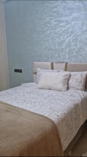 a bed with white sheets and pillows in a room at Appartement Marjana in Meknès