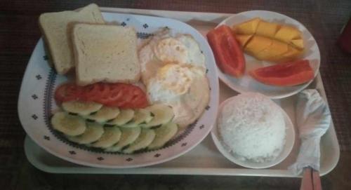 a tray with a plate of food with bread and fruit at Kubo Inn & Beach Camp in El Nido