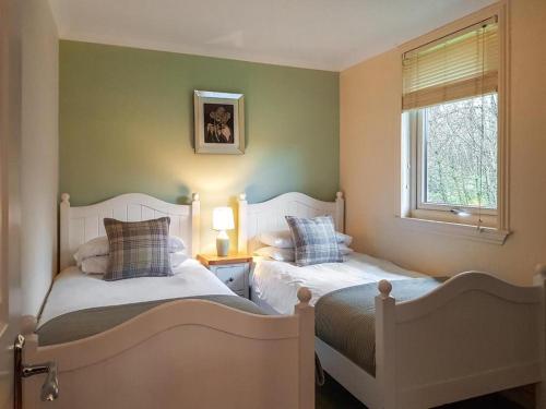 a bedroom with two beds and a window at Loch Lomond Sanctuary Lodges in Balloch