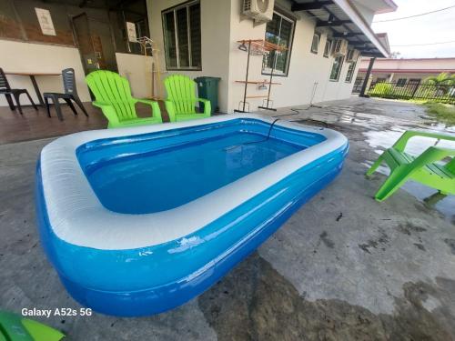 a blue swimming pool with green chairs in a yard at S99 HOMESTAY KUDAT in Kudat