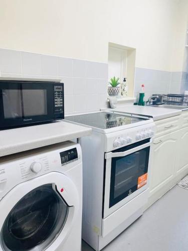 a kitchen with a washing machine and a microwave at YEBSS Apartment Colindale in Colindale