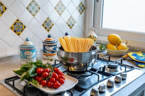 a stove with a pot of pasta and a plate of vegetables at Maiori Apartment by Marcel in Maiori