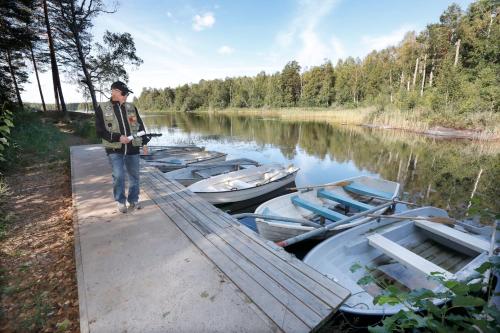 Człowiek stojący na przystani obok łodzi na rzece w obiekcie Konstnären Lenas hus. w mieście Bockara