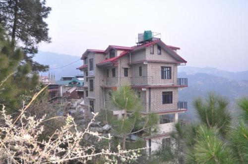 Jutogh的住宿－Hotel Thakur Home's Mountain View - Outdoor furniture - Picnic Area，山坡上树木的建筑物