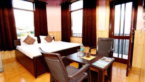 Habitación con cama, mesa y sillas. en Hotel Thakur Home's Mountain View - Outdoor furniture - Picnic Area, en Jutogh