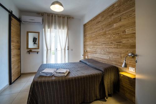 a bedroom with a bed and a wooden wall at Casadada in Santo Stefano di Camastra