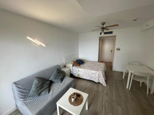 una sala de estar con un sofá y una cama en TORREMOLINOS CARIHUELA 1ª LINEA PLAYA, en Torremolinos