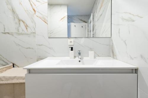 Baño blanco con lavabo y espejo en luxueux appartement 5 chambre, en Bruselas