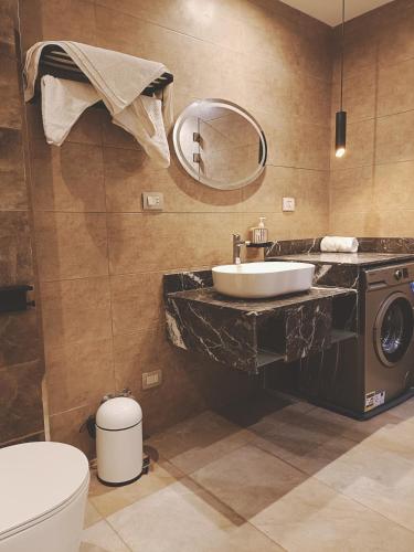 a bathroom with a sink and a toilet and a mirror at Aurora sky view suite in Sheikh Zayed