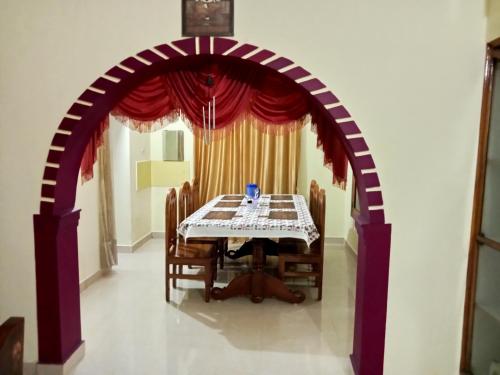 einen Torbogen in einem Esszimmer mit einem Tisch und Stühlen in der Unterkunft soms estate stay in Madikeri