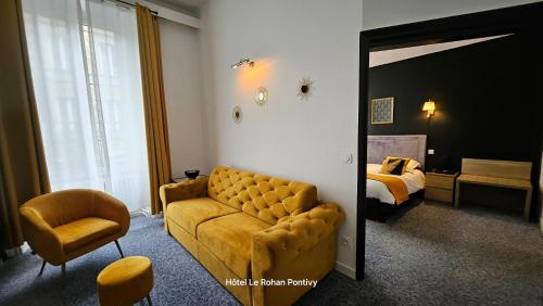 a living room with a couch and a bed at Hôtel Le Rohan Charme et Caractère in Pontivy