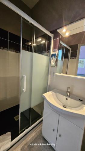 La salle de bains est pourvue d'un lavabo et d'une douche en verre. dans l'établissement Hôtel Le Rohan Charme et Caractère, à Pontivy