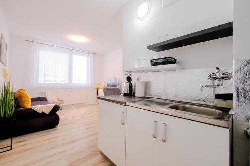 eine weiße Küche mit einem Waschbecken und ein Wohnzimmer in der Unterkunft Apartman Sweet home in Humenné