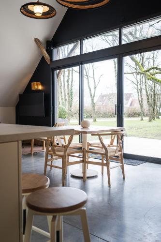 a dining room with a table and chairs and a large window at Charmantes Maisons avec spas privatifs au calme Idéal weekend à 2 en famille ou entres amis in Vierzon