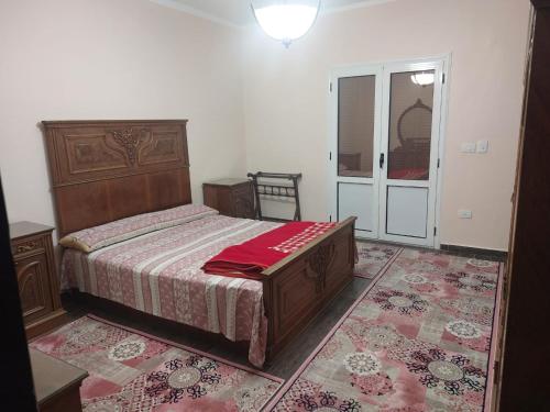 a bedroom with a bed with a red blanket on it at مصر الجديدة in Sīdī Sālim