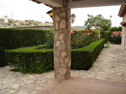 a stone pillar in a garden with bushes and flowers at Cuevas del Torreón -- Nueva Dirección in Castilléjar
