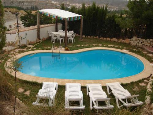 a pool with chairs and a table and an umbrella at Cuevas del Torreón -- Nueva Dirección in Castilléjar