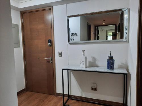 a bathroom with a table with a mirror and a door at Exclusive Apartment In San Damian, Vitacura in Santiago
