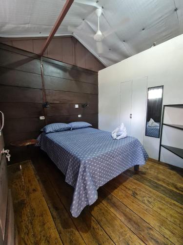 a bedroom with a bed with a blue comforter at Cabañas MOHES ballena in Uvita