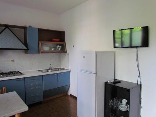 eine Küche mit einem Kühlschrank und einem TV an der Wand in der Unterkunft Chill and fun in our residence - Beahost in Bibione