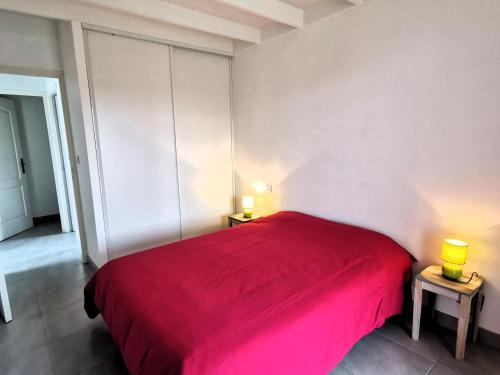 een rood bed in een witte kamer met 2 lampen bij Case Couleur proche de la mer in Brem-Sur-Mer