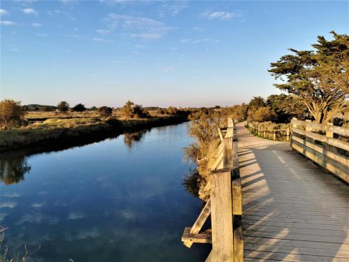 a wooden walkway over a river with a bridge at Case Couleur proche de la mer in Brem-Sur-Mer