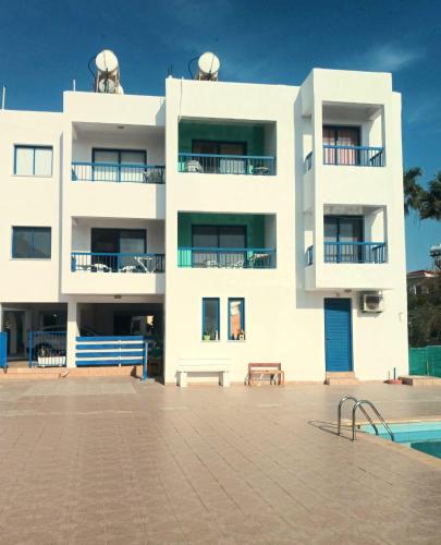 a white building with a swimming pool in front of it at Georgia Apartments in Paphos City