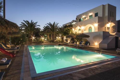 a swimming pool in front of a house at night at Petra Nera in Perissa