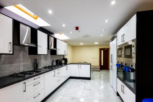 eine Küche mit weißen Schränken und schwarzen Arbeitsplatten in der Unterkunft Private Rooms With Private Bathrooms In Selly Oak Birmingham in Birmingham