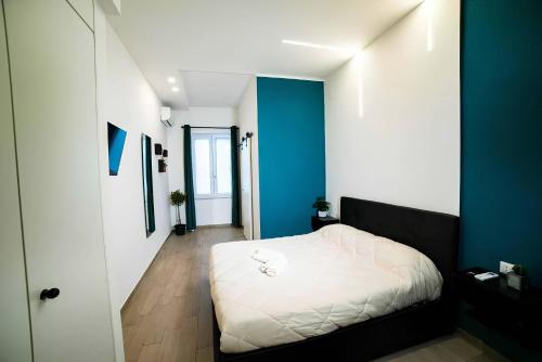 1 dormitorio con cama blanca y pared azul en Luxury GreenHouse Napoli-Sorrento-Pompei en San Vitaliano 