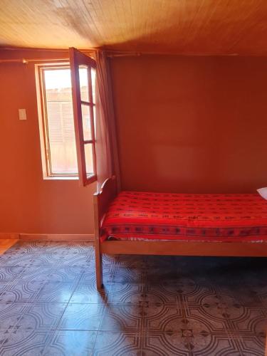 a bed in a room with a window at Hostal Candelaria in San Pedro de Atacama