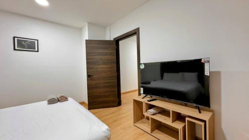 a bedroom with a flat screen tv and a bed at Edificio Tofino in Quito