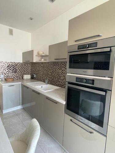 d'une cuisine équipée d'appareils en acier inoxydable et d'un évier. dans l'établissement Magnifique appartement avec vue sur mer, à Nice