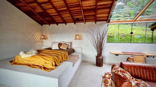 una camera da letto con un letto, un divano e una finestra di Cabana Rinoceronte a São Bento do Sapucaí