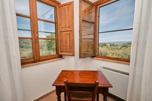 a dining room with a table and two windows at 8380 Agriturismo il Saragiolo in Manciano