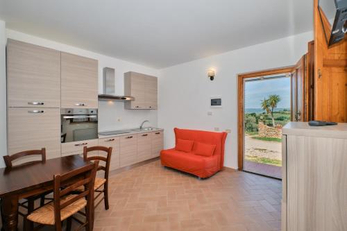 a kitchen with a dining table and a red chair at 8380 Agriturismo il Saragiolo in Manciano