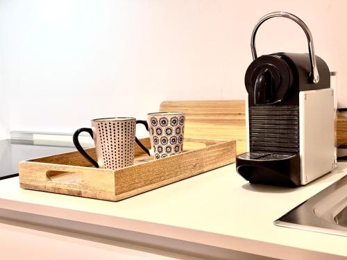 una encimera de cocina con 2 tazas de café y una tabla de cortar en ComeCasa Larga Cosy Studio en Milán