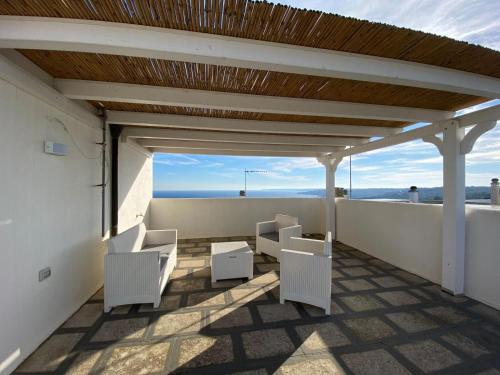 uma varanda com cadeiras brancas e um telhado de madeira em Aurora em Santa Cesarea Terme