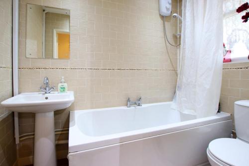 a bathroom with a sink and a tub and a toilet at 3 bedrooms Sleeps 8 Self Catering House Near California Cliffs and Great Yarmouth Beach,Norfolk in Earlham