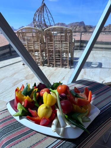 a plate of vegetables on a table with a window at Hasan Zawaideh Camp in Wadi Rum